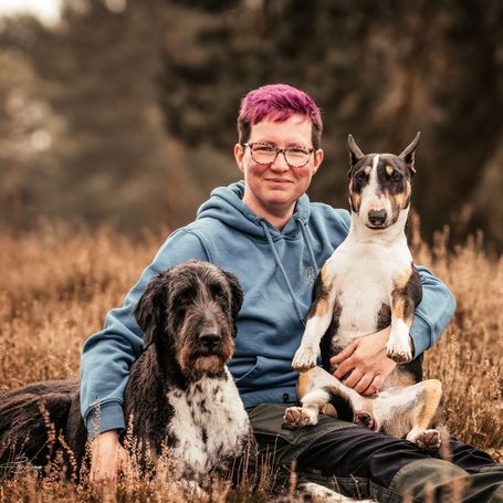 Eine Frau sitzt auf einer Bank und links und rechts daneben ein Hund